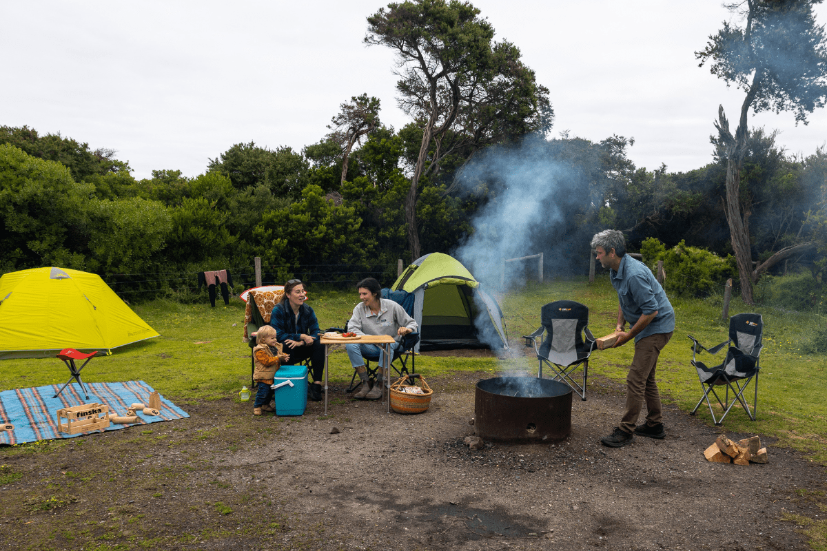Family sitting around campfire in a designated campground area