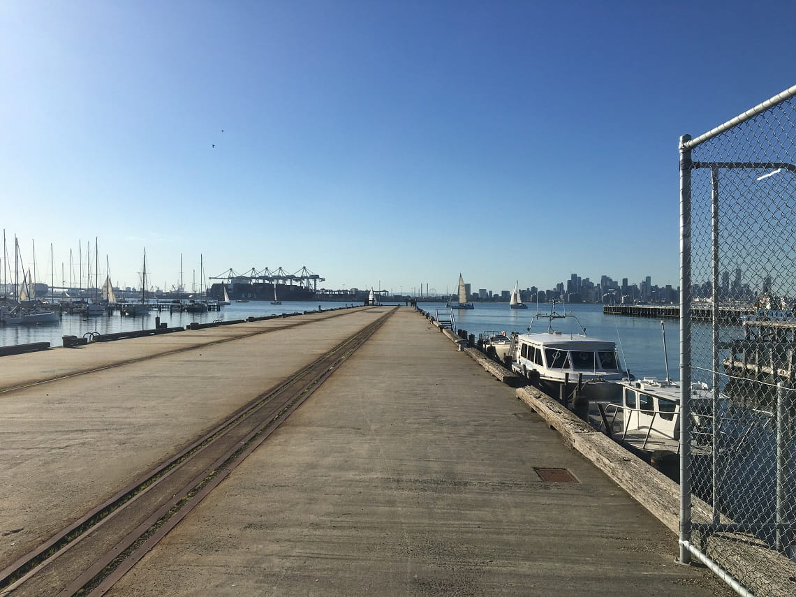 Concrete pier extending into Hobsons Bay with Melbourne city skyline to the horizon