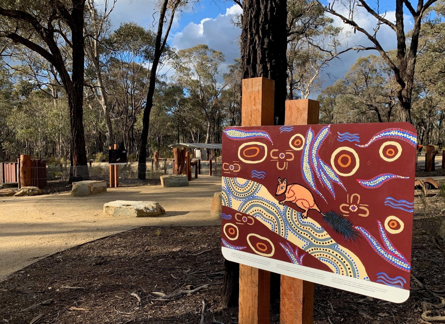 Artistic sign in foreground and campground surrounds and forest in background