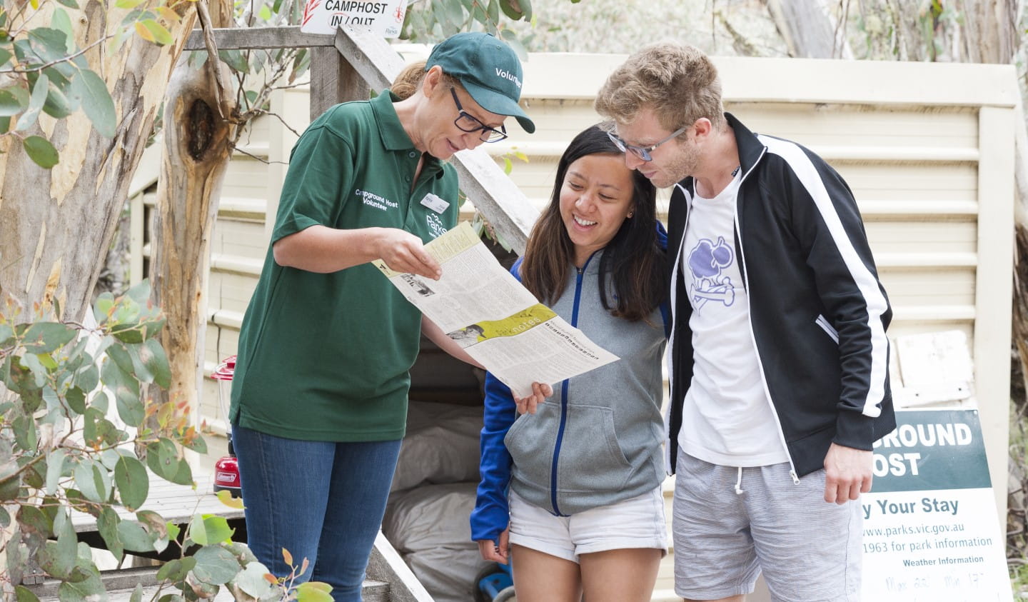A volunteer campground host helps two people.