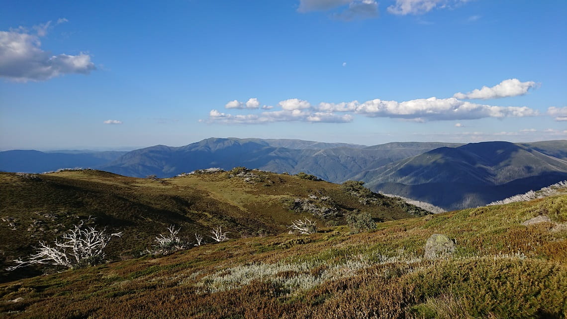 Mountainous rolling hills of the Victorian alps with a bright blue sky