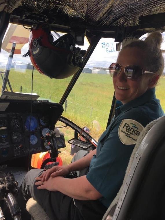 Rhianna sits smiling in the cockpit of a helicopter, wearing her Parks Victoria uniform