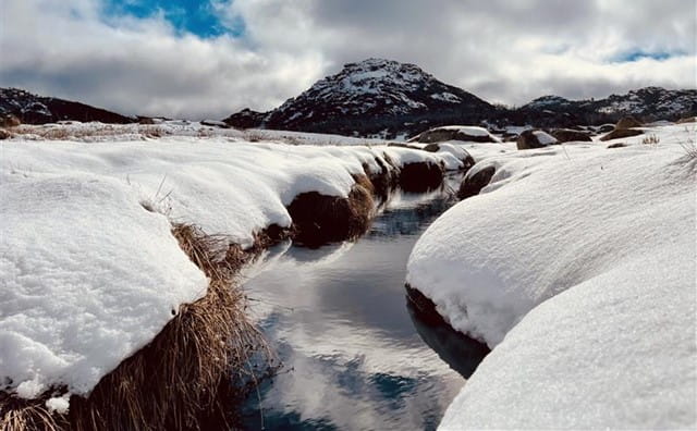 A ravine between two snow covered banks looking up at Mount Buffalo after the first snowfall of the season