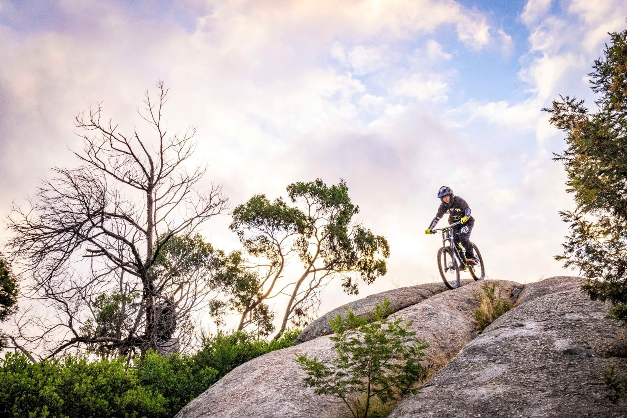 a person is riding a bike and riding down a large rock