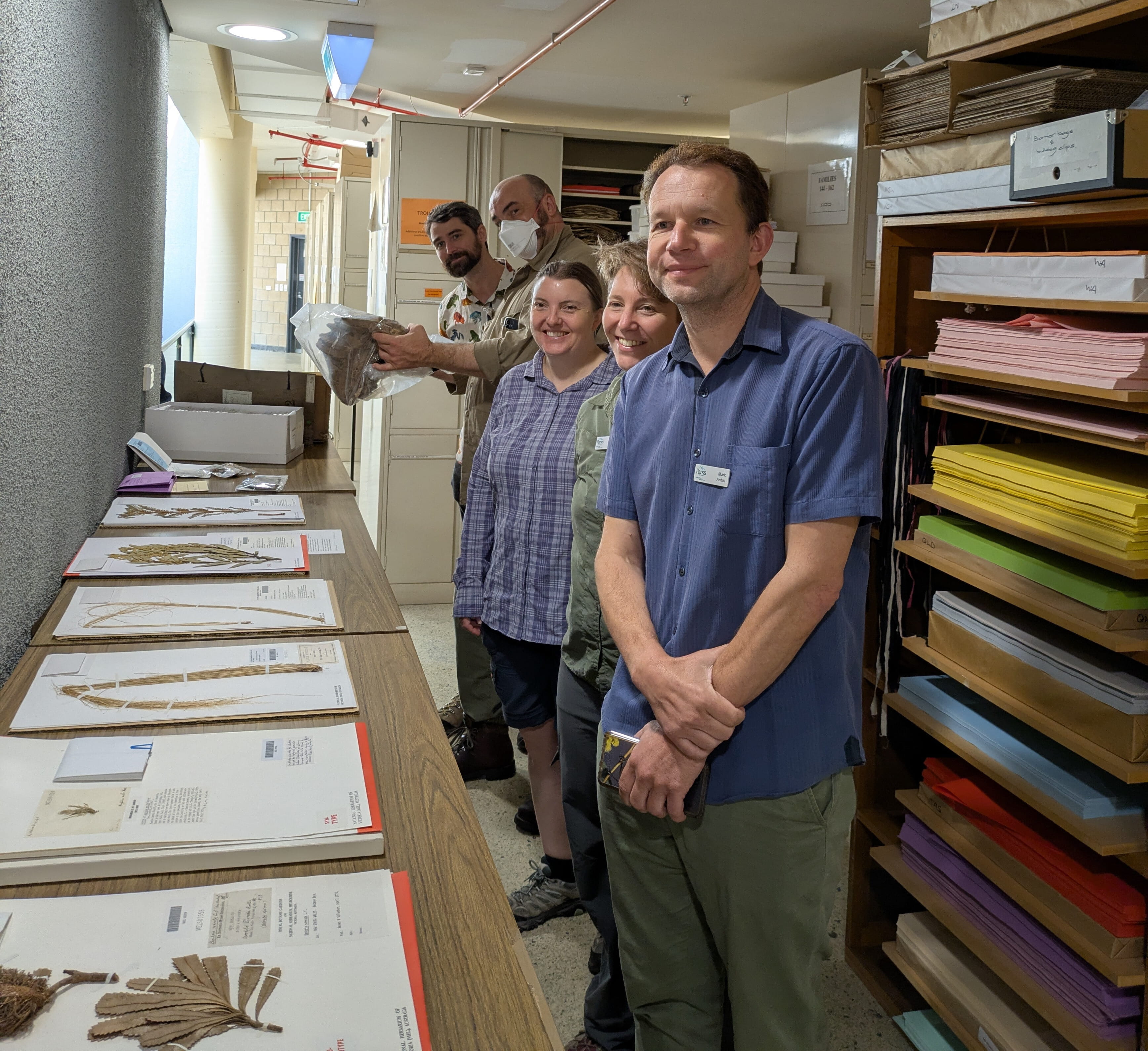 Team of scientists smiling at the camera, in front of them is a lay of specimens 