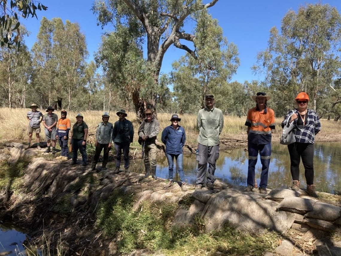 Eleven people stand atop the sandbag structure at Rowan Swamp