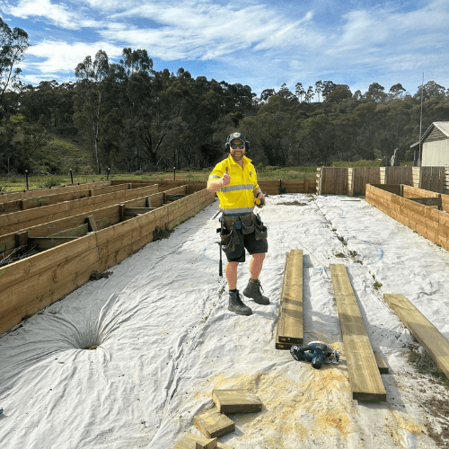 Brandon standing in his Parks Victoria uniform, surrounded by a carpentry work in progress