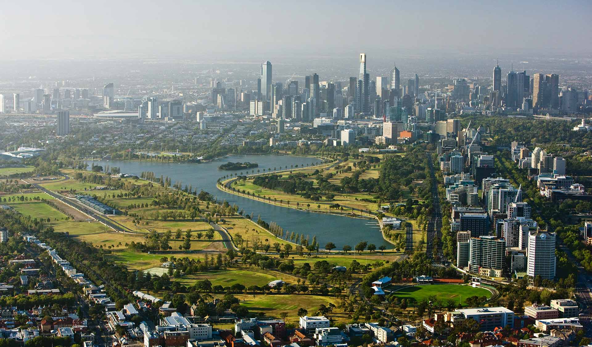 An aerial view of Albert Park Lake with the Melbourne CBD skyline in the background.