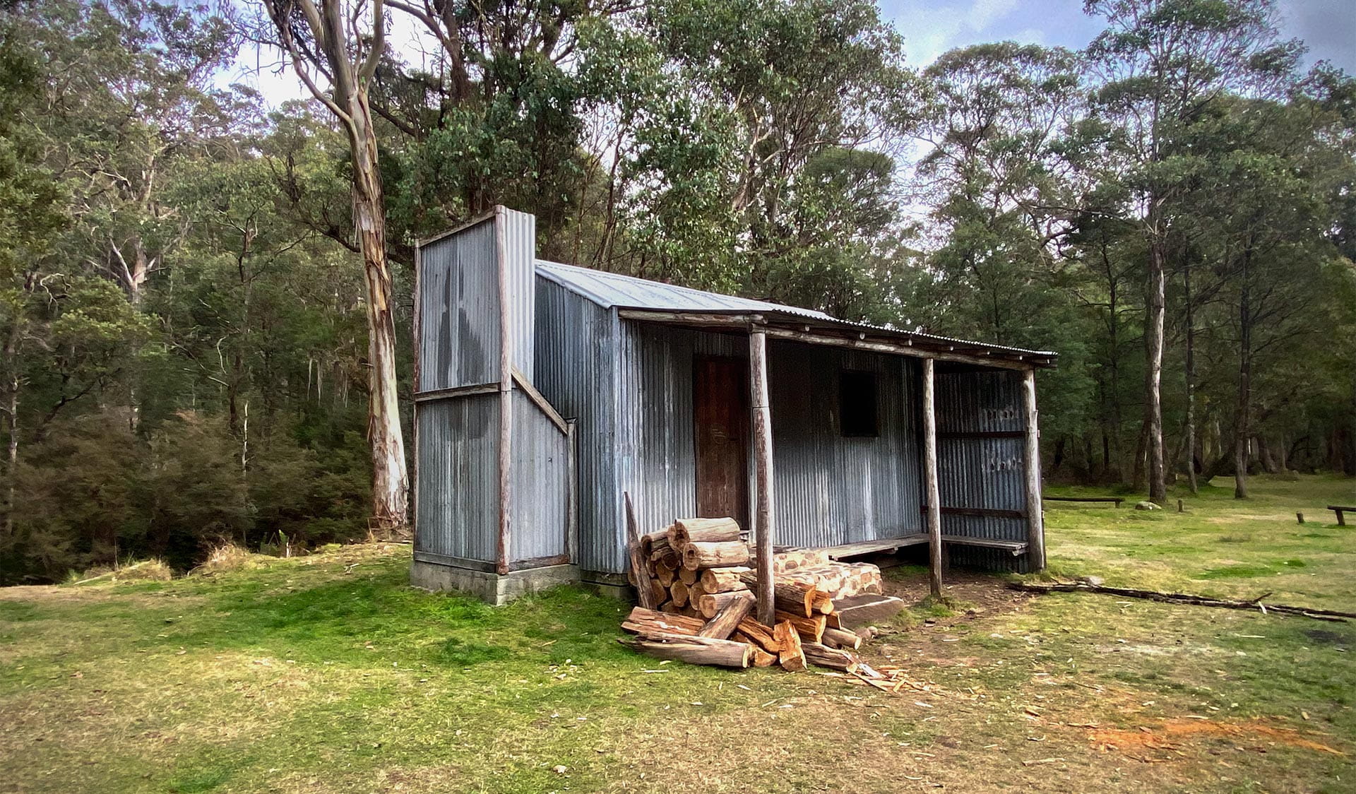 View of a hut with chopped wood piled up outside.
