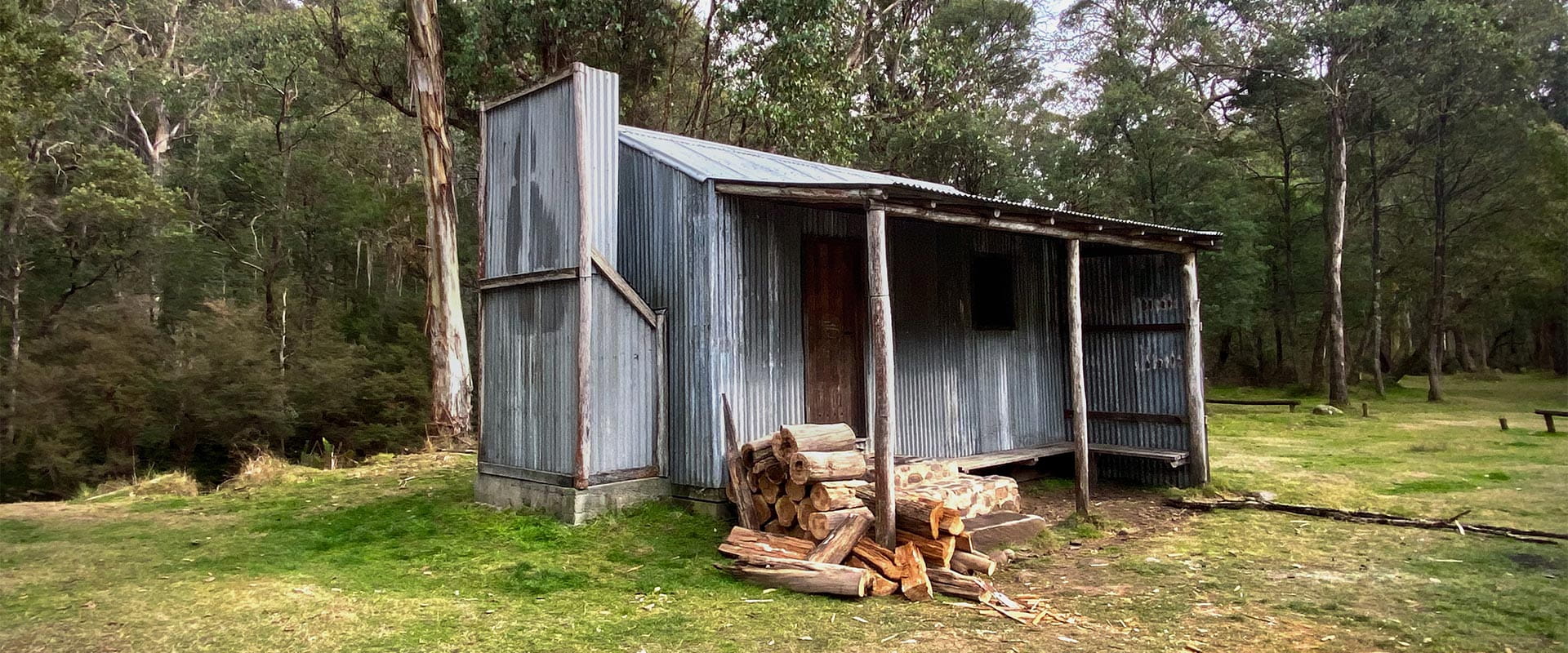 View of a hut with chopped wood piled up outside.