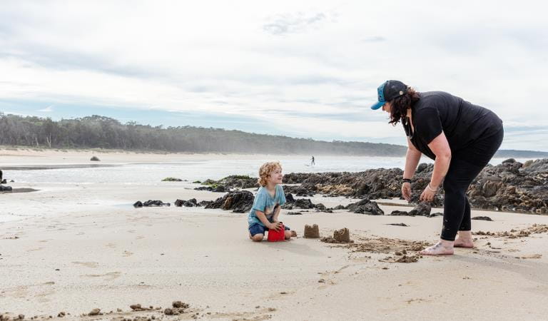 A woman and child play in the sand.
