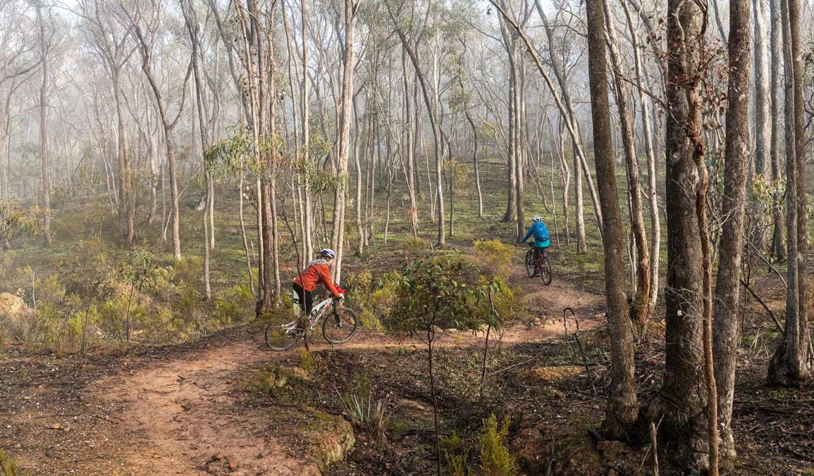 Two women ride mountain bikes along the Goldfields track near Castlemaine.