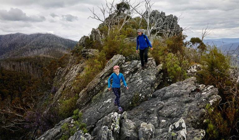 A mother and young daughter walk across Sugarloaf Saddle in magnifficent panoramic views either side of them.