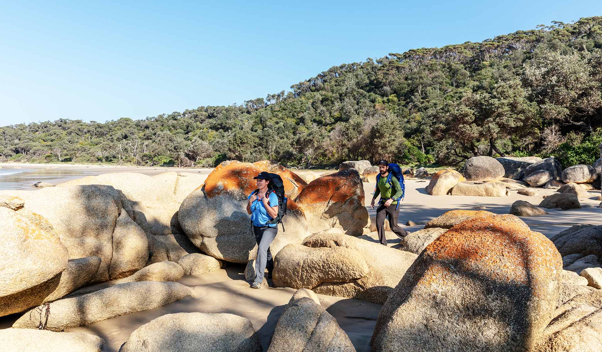 A man and a women on a long hike walk between the rocks nears Point Hicks.