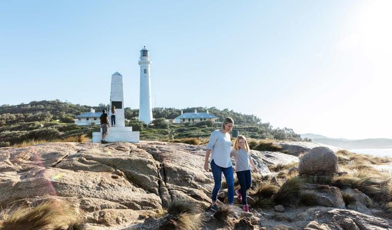 A mother and daughter in front of the Point Hicks Lighthouse and cottages.