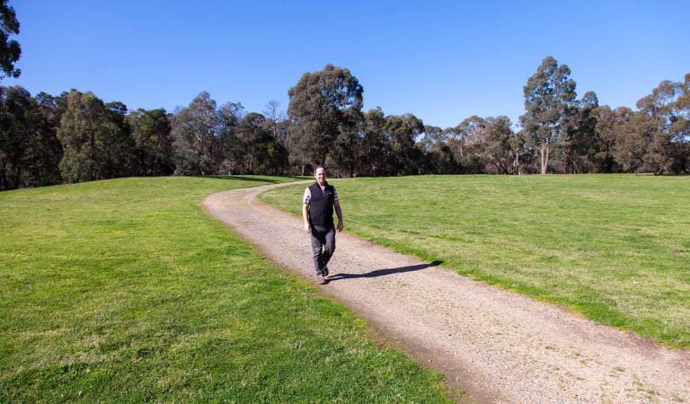 A man walks along the path at the Brady Road Picnic Area at Dandenong Police Paddocks Reserve
