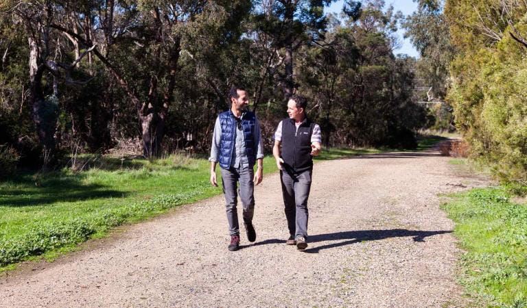 Two friends mid conversation walking along Brady Road in Dandenong Police Paddocks Reserve
