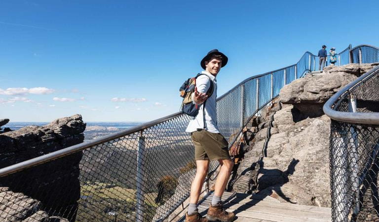 A young man offers his hand to his walking partner at the summit of The Pinnacle in the Grampians National Park.