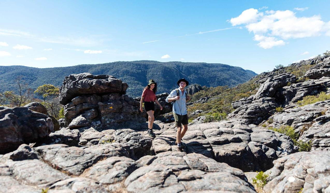 A young couple walks up through ancient lava flows to the Pinnacle in the Central Grampians.