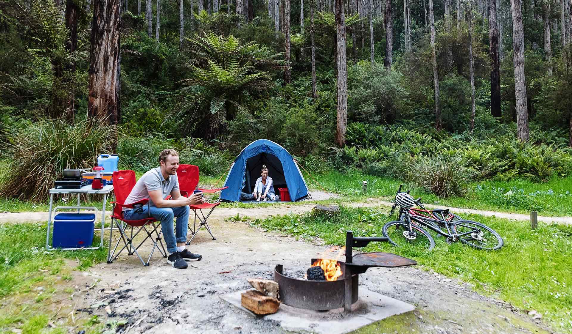 A couple in their later twenties enjoy a joke while at their campsite at Lake Elizabeth Campground in the Great Otway National Park.
