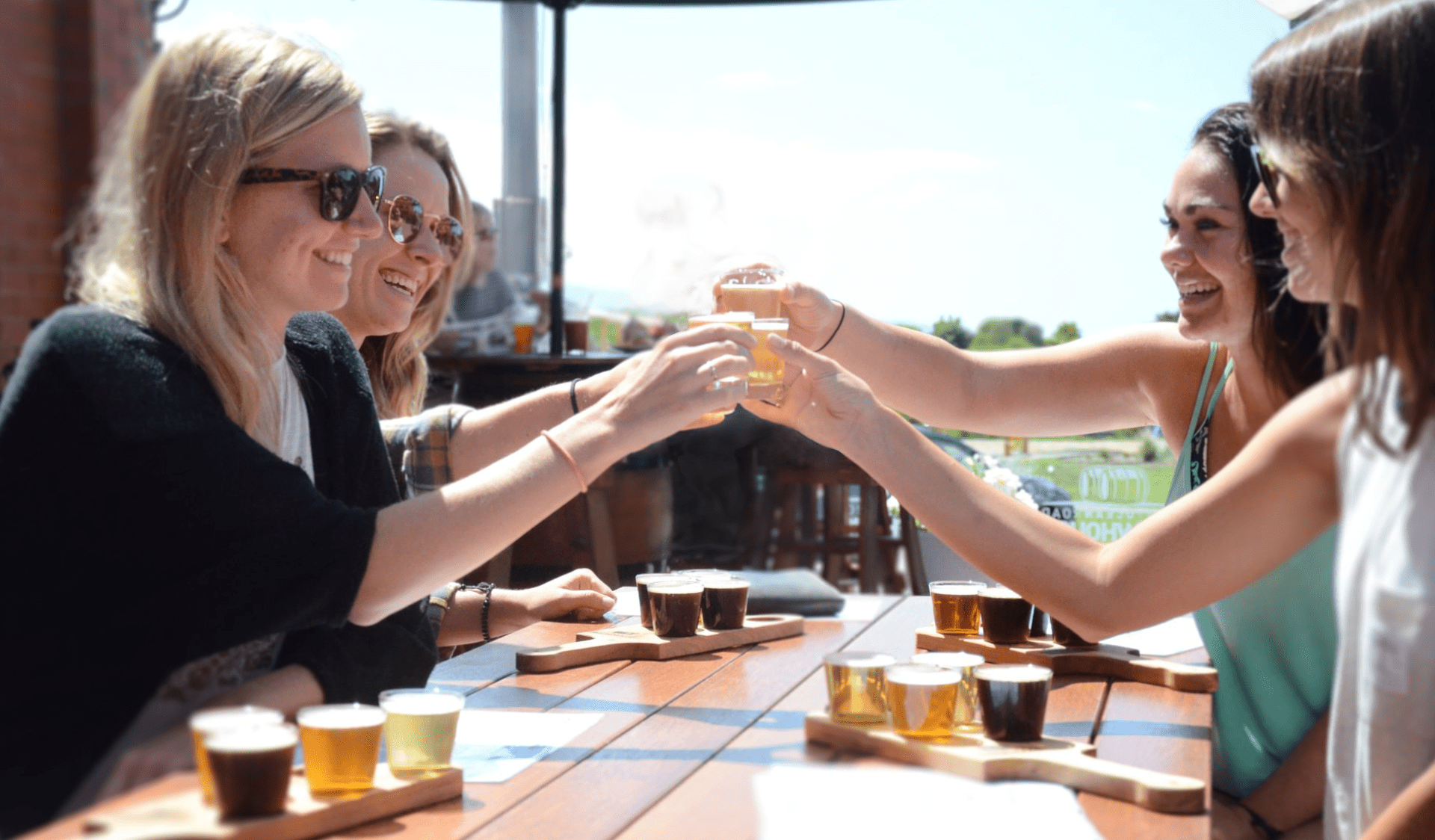 Four friends with tasting paddles do cheers