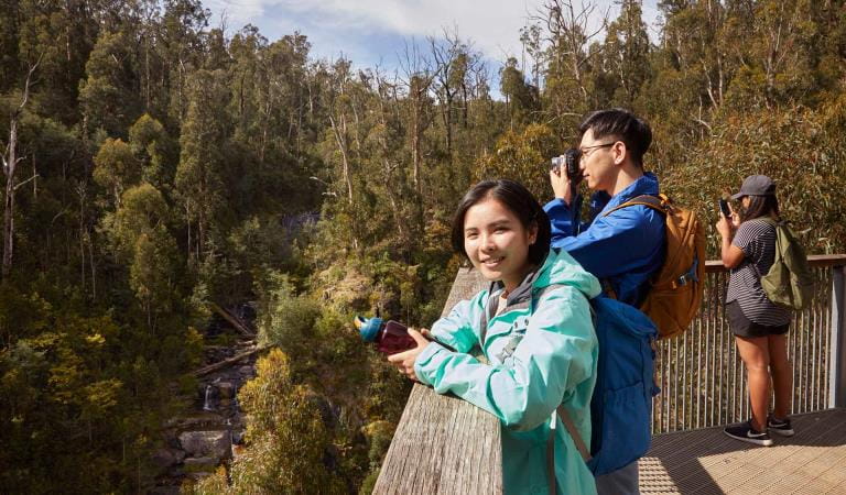 A husband and wife stop to take a photo of Masons Falls from the lookout.