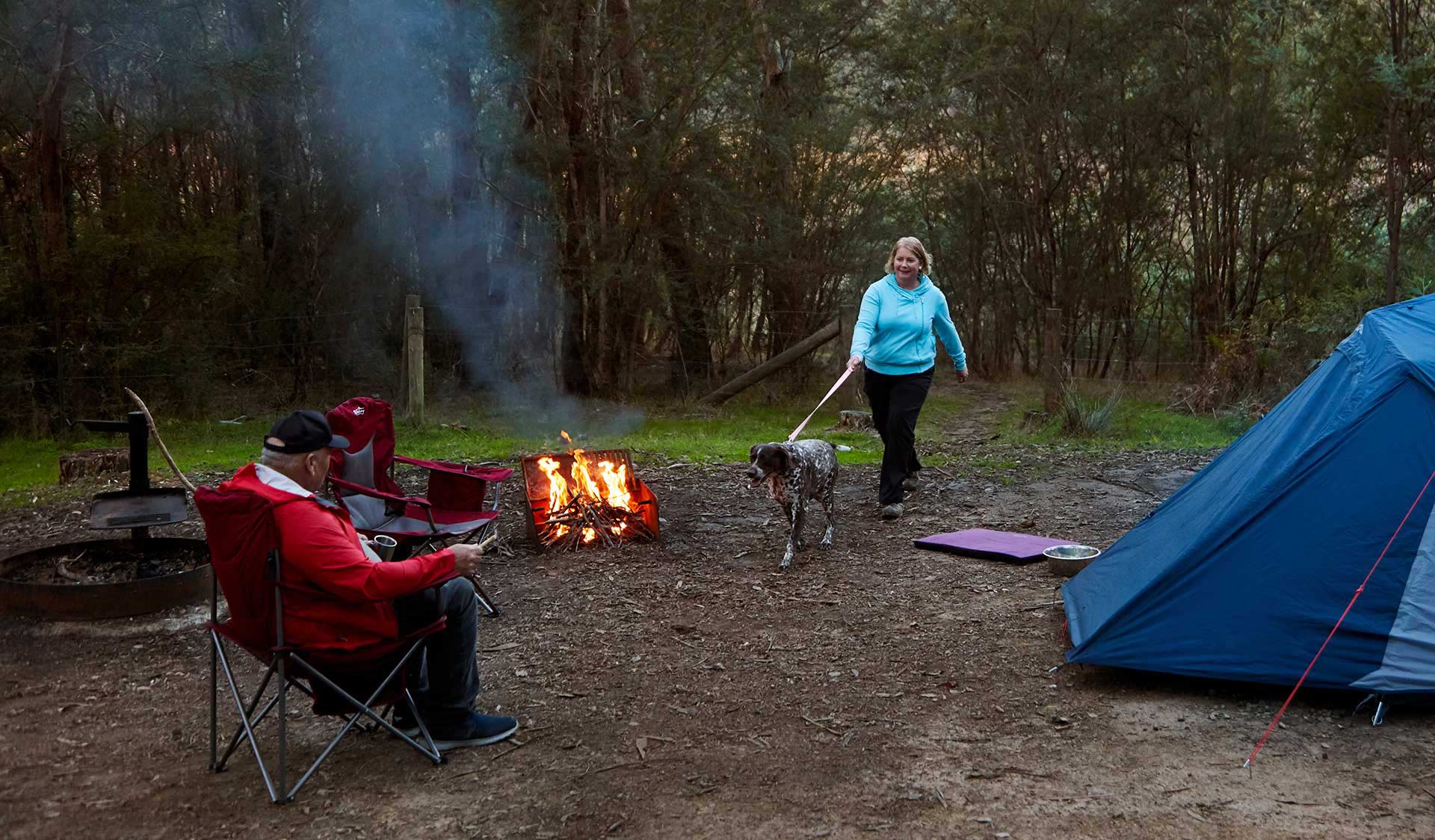 A couple and their dog camp around a fire at Jerusalem Creek camp ground.