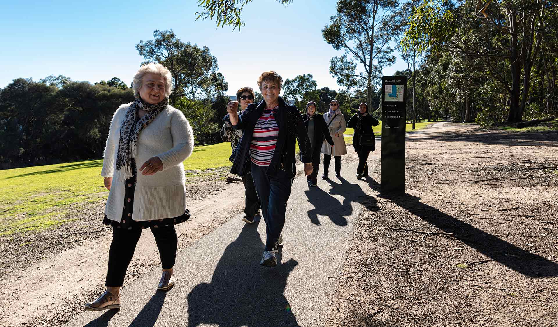 A group of older women walk along a path in Lysterfield Lake. 