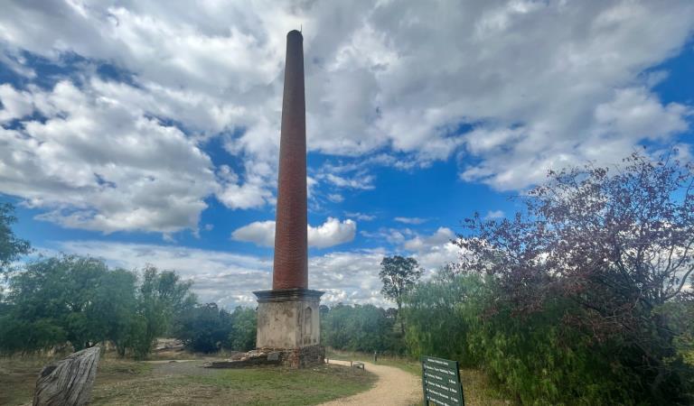 A tall brick chimney stands in an open field