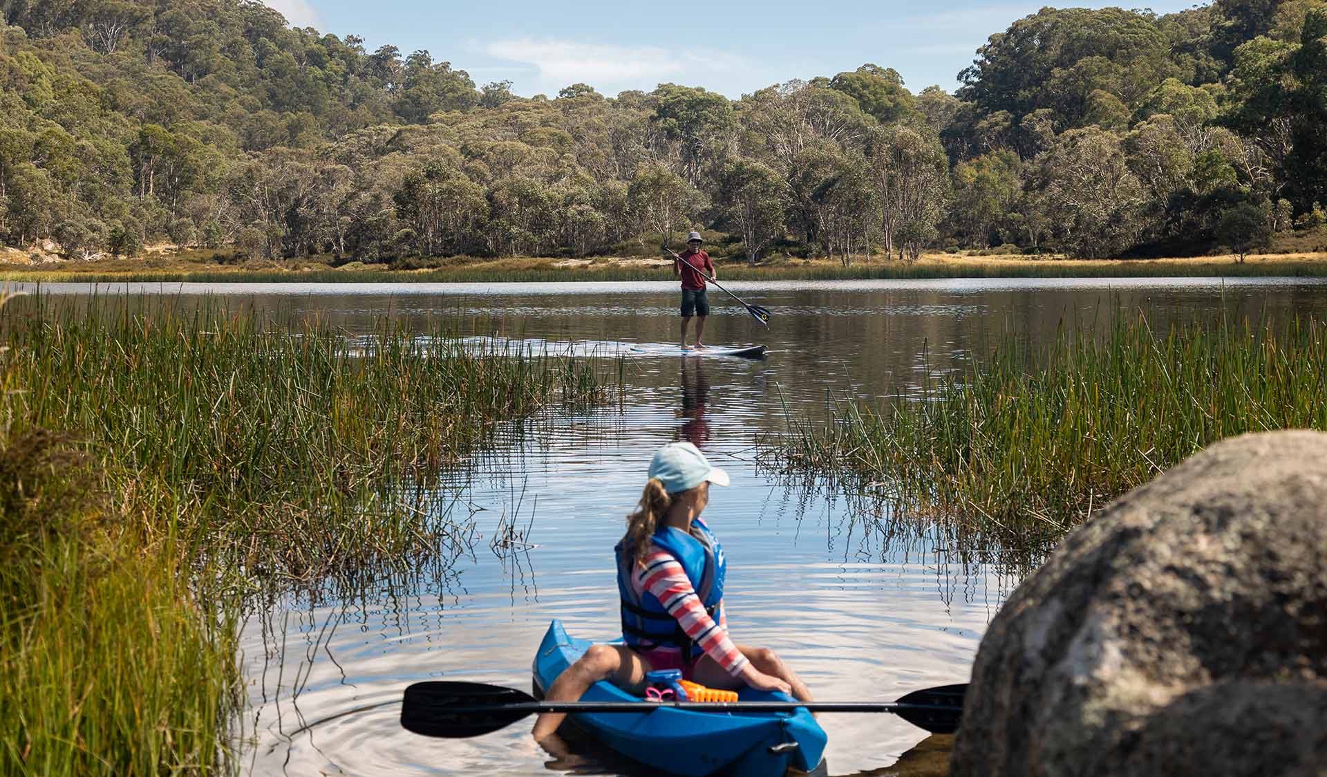 A young girl waits for her father who is paddling a SUP not far behind her on Lake Catani