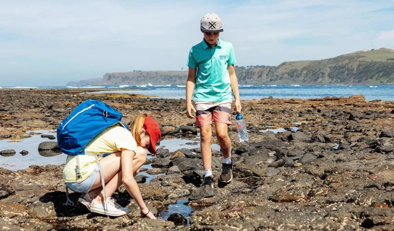 Two children walk through the rockpools at Mushroom Reef.