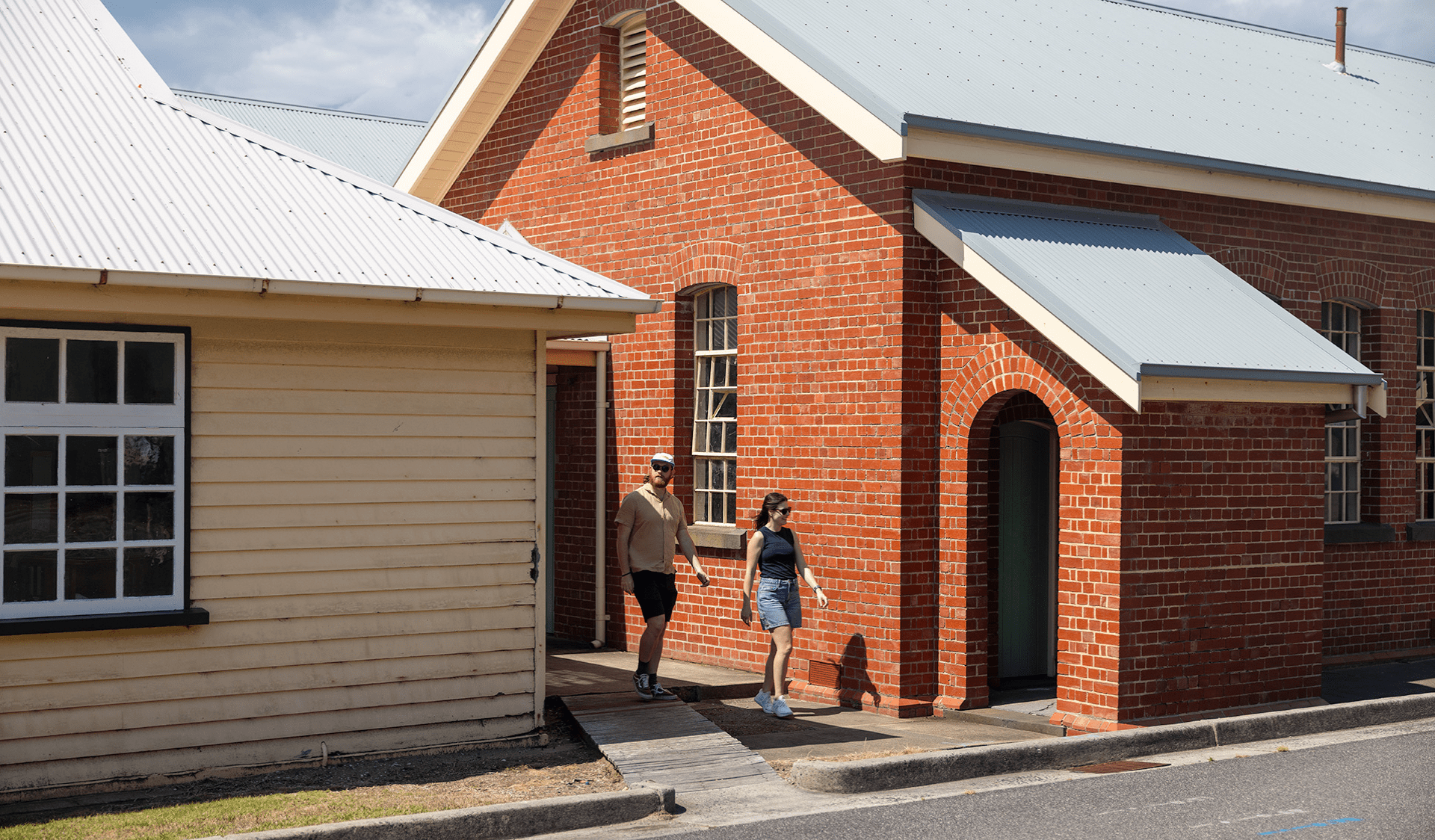 Woman and man walking between two buildings.