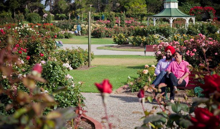 A couple sit on a bench in the rose garden at Werribee Park.