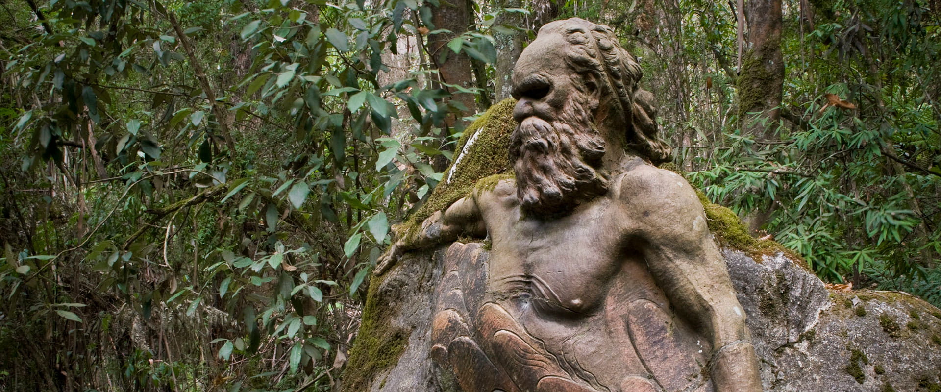 Sculpture by William Ricketts surrounded by lush green foliage. 