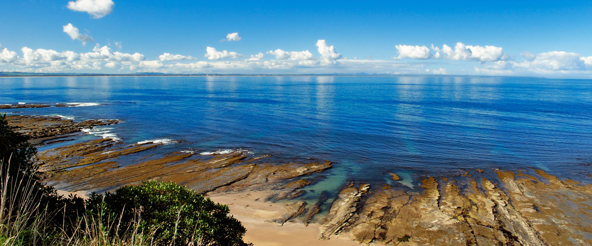 A view point that overlooks the marine park and ocean on a sunny day with distant clouds and calm waters