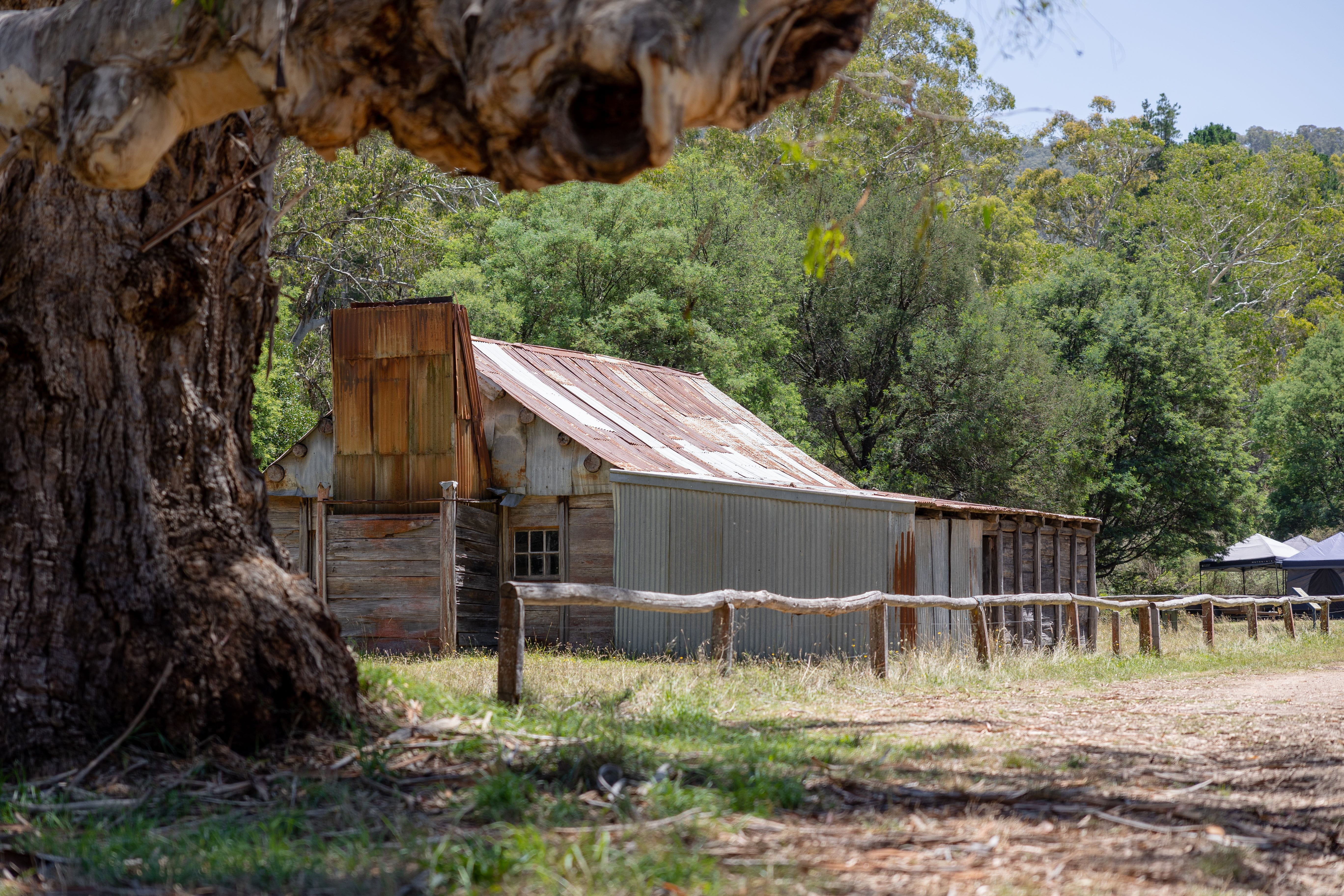 A large shed surrounds by grass and trees.
