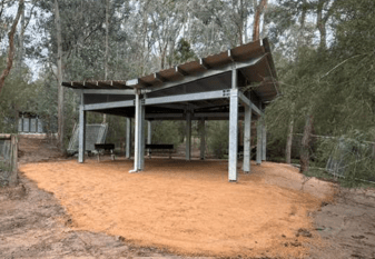 New education shelter at Candebark Campground, providing an all-weather covered space for visitor education and group activities. The structure features durable steel construction, an open design, and integration within the surrounding bushland environment.