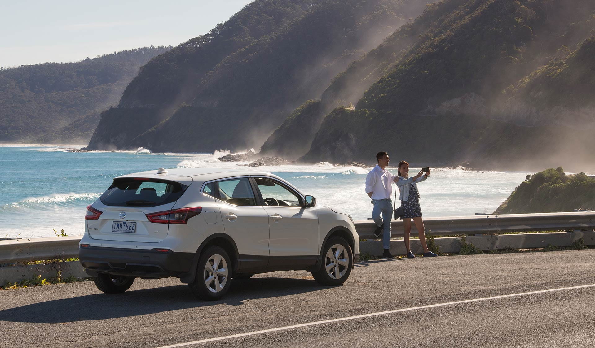 A couple stop on the side of the Great Ocean Road to take a picture.