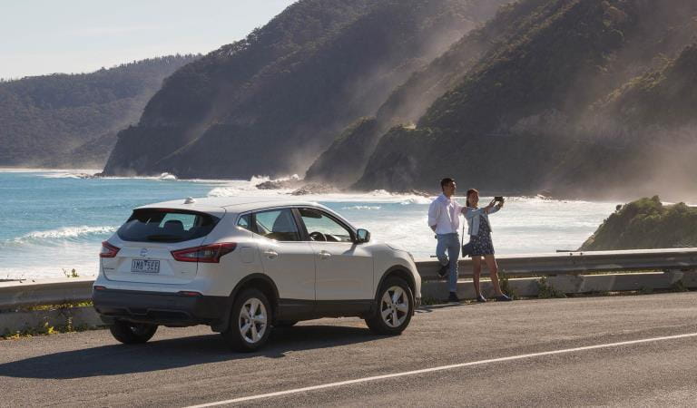 A couple stop on the side of the Great Ocean Road to take a picture.
