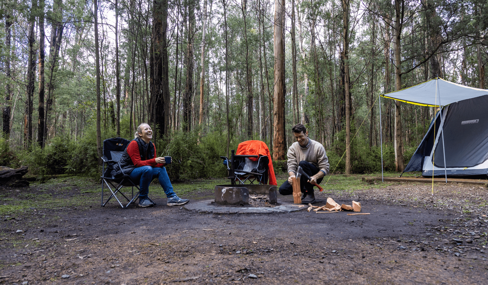 Couple soaking in the serenity at The Gums Campground, Kinglake National Park around a campfire.