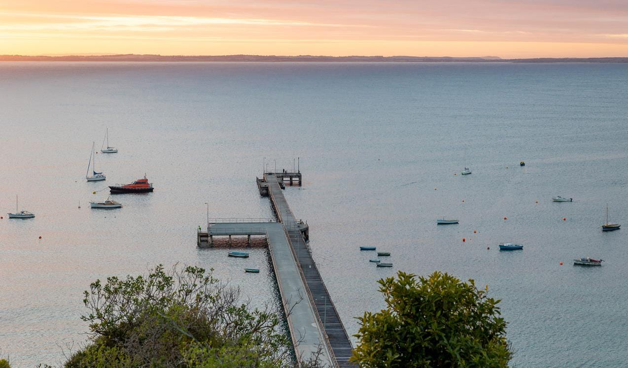 a pier and harbour with boats at sunrise